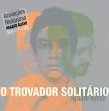 Grey square with three overlapped pictures of Renato Russo's bust (one green, one orange and one dark grey). 'O Trovador Solitário' is written in capital letters and 'Renato Russo' is written in a smaller fonte right below and to the right. A sticker at the top-left corner of the image says 'Gravações Históricas Renato Russo Voz & Violão', which translates as 'Historic Recordings Renato Russo Voice & Acoustic Guitar'