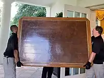 Two men carrying the desk top out of the opal office