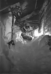 A man crawls through a passageway filled with snow