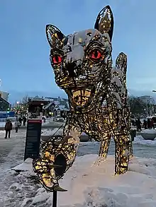 image of a holiday decoration featuring a black cat with large claws and teeth, covered in snow