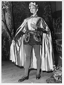 Man wearing a hat, doublet, hose, and cape