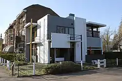 A modernist-style house in front, older brick houses in the background