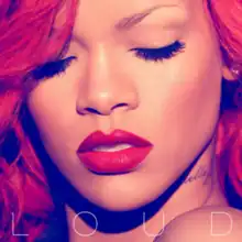 A close up of Rihanna's face with long wavy red hair, both of her eyes are closed and she is wearing bright red lipstick. Towards the bottom of the picture is the word "LOUD" written in a white font.