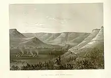 An achromatic illustration of low mountains, with a camp formation on the flat plain in the distance to the left, which one two figures wearing cowboy-style hats in the foreground center points at. Below is the text "Rio San Pedro—Above Second Crossing".