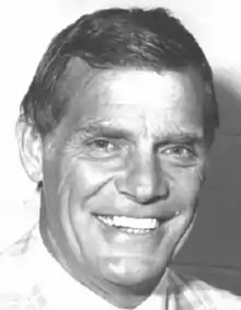 Black and white facial photo of a smiling elder man in a white dress shirt