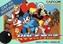 Image of a baby blue, rectangular box. The bottom portion reads "Rockman" along with a Nintendo Family Computer label below, while the artwork depicts a human robot boy in a blue outfit running from several robot characters. The landscape is a rocky valley with what appears to be a white structure in the distance.