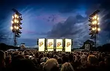 The Rolling Stones Stage at Hamburg Stadtpark. It shows the crowd in the foreground and the huge yellow illuminated screens of the stage in the background.