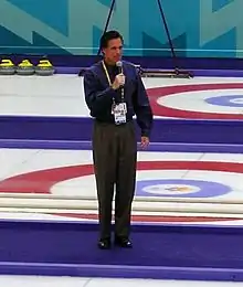 Photograph of Romney standing with microphone in middle of curling lanes
