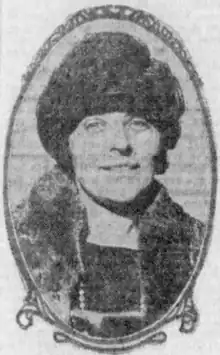 A young white woman wearing a dark hat and a fur coat, in an oval frame