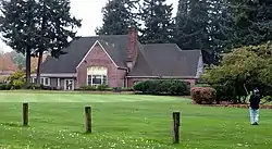Photograph of the Rose City Golf Clubhouse, with a golfer in the foreground