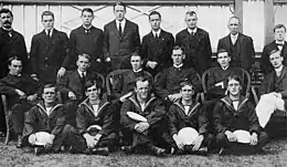 A group of 19 men arranged in three rows, many of them in naval uniforms