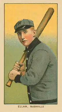 A baseball card of a man in a gray baseball uniform trimmed with black stands facing the left, holding his bat, preparing–swing.