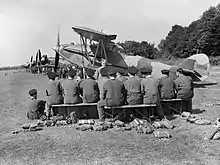 Apprentices of No. 1 School of Technical Training listen to a lecture on servicing aircraft in the field, in front of a line of instructional airframes, during the early 1940s.