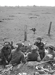 Sergeant F. Beal (fourth from left), Canadian Army Film and Photo Unit, talking with infantrymen of the Royal Hamilton Light Infantry (R.H.L.I.), Speldrop, Germany, 24 March 1945.