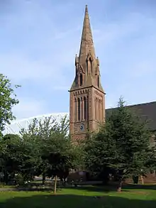The tall steeple of a sandstone church with prominent lucarnes
