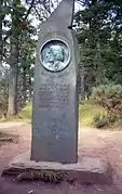 monument in the form of an irregular stone bearing a relief sculpture profile and a memorial text