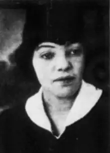 A young Black woman with light skin, wearing an academic cap and gown