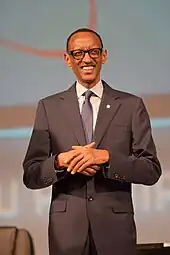 Picture of Kagame, standing, wearing a dark suit with purple tie