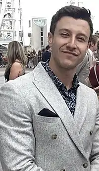White man in a grey suit smiling