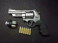 Left side view of a S&W Mountain Gun M625-6 .45 LC revolver, 4" barrel, with 250 gr. .45 LC rounds and a speedloader filled with home defense 250 gr. XTP