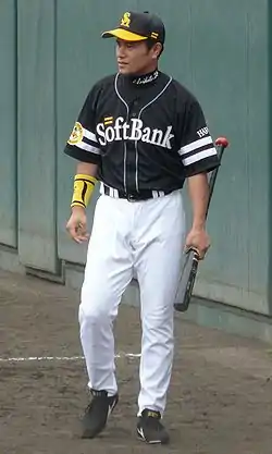 Arihito Muramatsu wearing a black baseball uniform with "SoftBank" across the chest in white script standing and holding a baseball bat