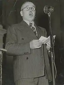 Portrait of Tom Garland, speaking into a microphone at a conference