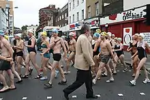 picture shows a group of people wearing swim wear walking along a London Street