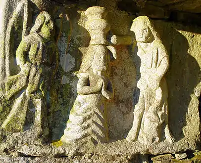 The baptism scene in the niche of the Kerbreudeur calvary. Three people are depicted, Jesus, John the Baptist and an angel who holds Jesus' robe whilst the baptism takes place.