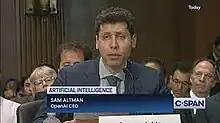 Sam Altman seated in front of microphone