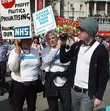 three people demonstrating holding placards