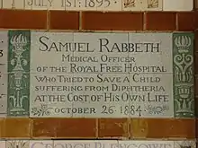 A tablet formed of six standard sized tiles, bordered by green flowers in the style of the Arts and Crafts movement