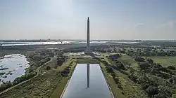 A tall monument with a star at the top in front of a reflection pool