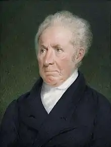 An old man with gray hair combed back and black coat