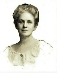 B&W portrait photograph of a blonde woman with her hair in an up-do, wearing a pale, scoop-neck blouse