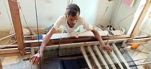Saris often use cloth a bit wider than the wearer's waist height, and may, as here, be close to the maximum width a weaver can span. Mothkur, Telangana State, India
