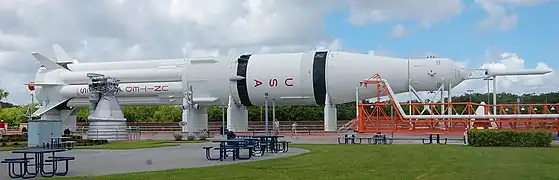 A large white rocket, with the letters U,S and A written vertically down it in red, lies on its side outdoors