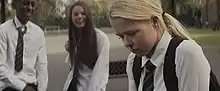 A shot of two school students smiling and harassing a schoolgirl, with blood running down the latter's nose.