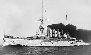 A large white warship with gray superstructure; several men are standing on the bow