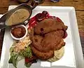 Schnitzel platter consisting of veal, pork, and chicken schnitzels, served with mashed potatoes, beetroot, mushroom cream sauce and side salad