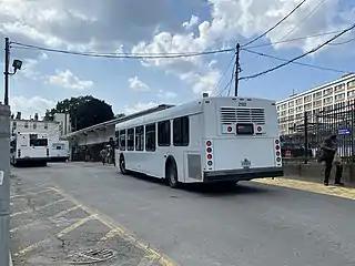 Two white buses in a busway at a disused light rail station
