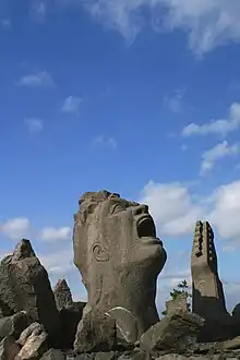 A sculpture of a man's head screaming at the sky with a guitar by its side, carved out of volcanic rock.