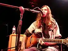 One male guitarist performing on an indoor stage