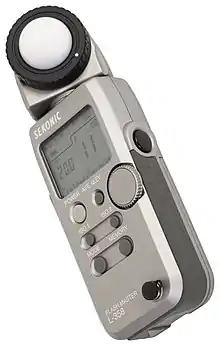 A handheld digital light meter showing an exposure of .mw-parser-output .frac{white-space:nowrap}.mw-parser-output .frac .num,.mw-parser-output .frac .den{font-size:80%;line-height:0;vertical-align:super}.mw-parser-output .frac .den{vertical-align:sub}.mw-parser-output .sr-only{border:0;clip:rect(0,0,0,0);clip-path:polygon(0px 0px,0px 0px,0px 0px);height:1px;margin:-1px;overflow:hidden;padding:0;position:absolute;width:1px}1⁄200th at an aperture of f/11, at ISO 100. The light sensor is on top, under the white diffusing hemisphere