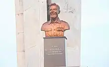 A metal bust of Cornelius Francis Adjetey from the chest up, on a stone pedestal