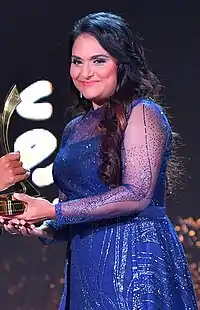 Sheela receiving an award with a smile