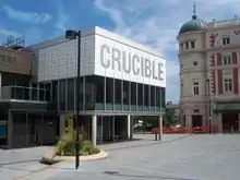 A building with the word "Crucible" emblazoned on white tiles above a raised windowed area.