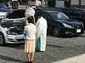 A priest waves Onusa at a car