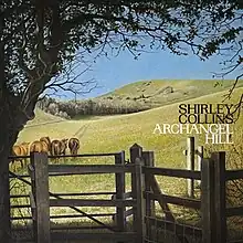 A pastoral scene with horses walking toward green hills