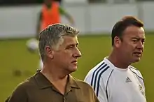 Two men with a player warming up behind them