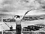 A signalman sends a semaphore message from a Pearl Harbor Control Tower, c. 1960.